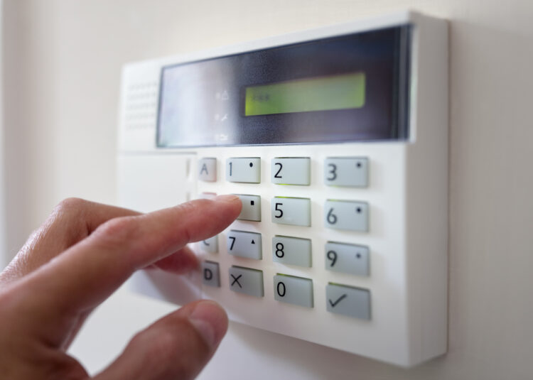 kobieta ustawia alarm domowy chroniący mieszkanie przed złodziejami